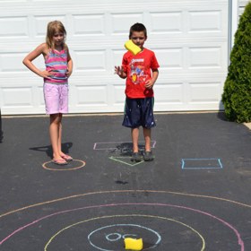 3. Namalujte křídami terč na zem a linii, od které se bude házet. Namísto šipek použijte houbičky na mytí nádobí či cokoliv jiného.