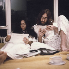 březen 1969

John a Yoko věděli, že se o ně po jejich svatbě začne ohromně zajímat tisk, proto se rozhodli toho využít k propagaci úsilí o světový mír.  Strávili týden (od 25. do 31. března) v prezidentském apartmá číslo 702 v hotelu Hilton v Amsterdamu a mezi devátou ranní a devátou večerní k nim každý den mohli chodit novináři.
