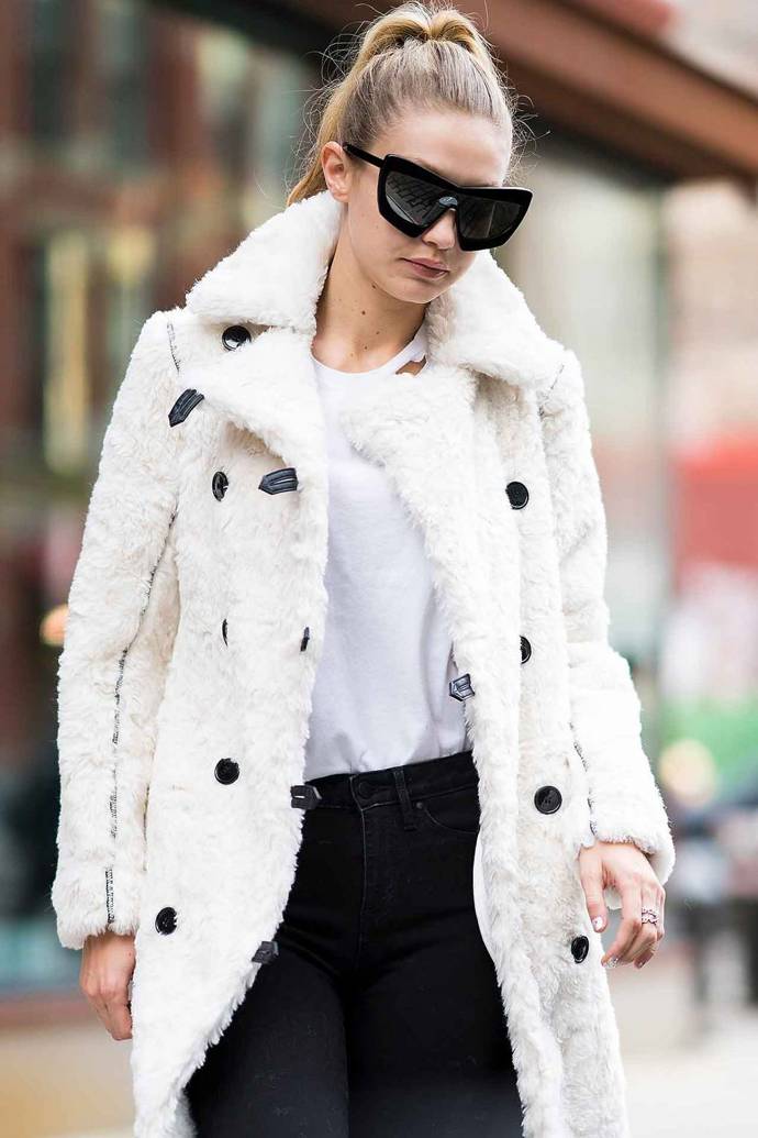 Huňatý bílý kabát a oversized sluneční brýle, to je zimní outfit podle Gigi Hadid
