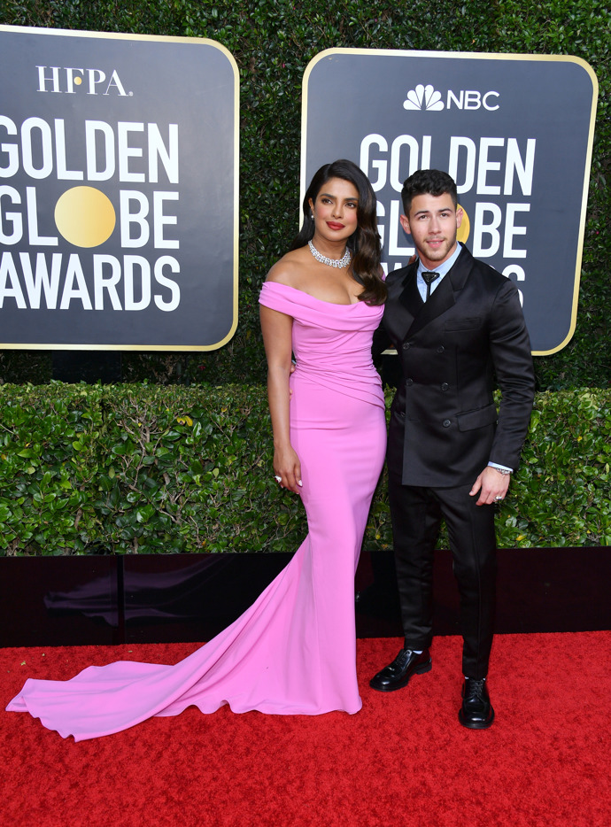Priyanka Chopra Jonas růžovou róbu doplnila šperky Bulgari a botami Christian Louboutin a její manžel Nick Jonas zvolil luxusní hodinky a prsten rovněž od Bulgari
