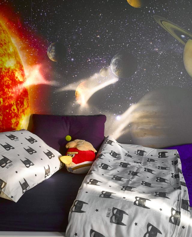 Tapetu s planetami sluneční soustavy designérka umocnila modrou výmalbou. Barevné stropy obecně místnost opticky snižují, ale právě proto se skvěle hodí do dětských pokojů. Vnáší do nich útulnou atmosféru, kterou si jejich malí obyvatelé zamilují.
