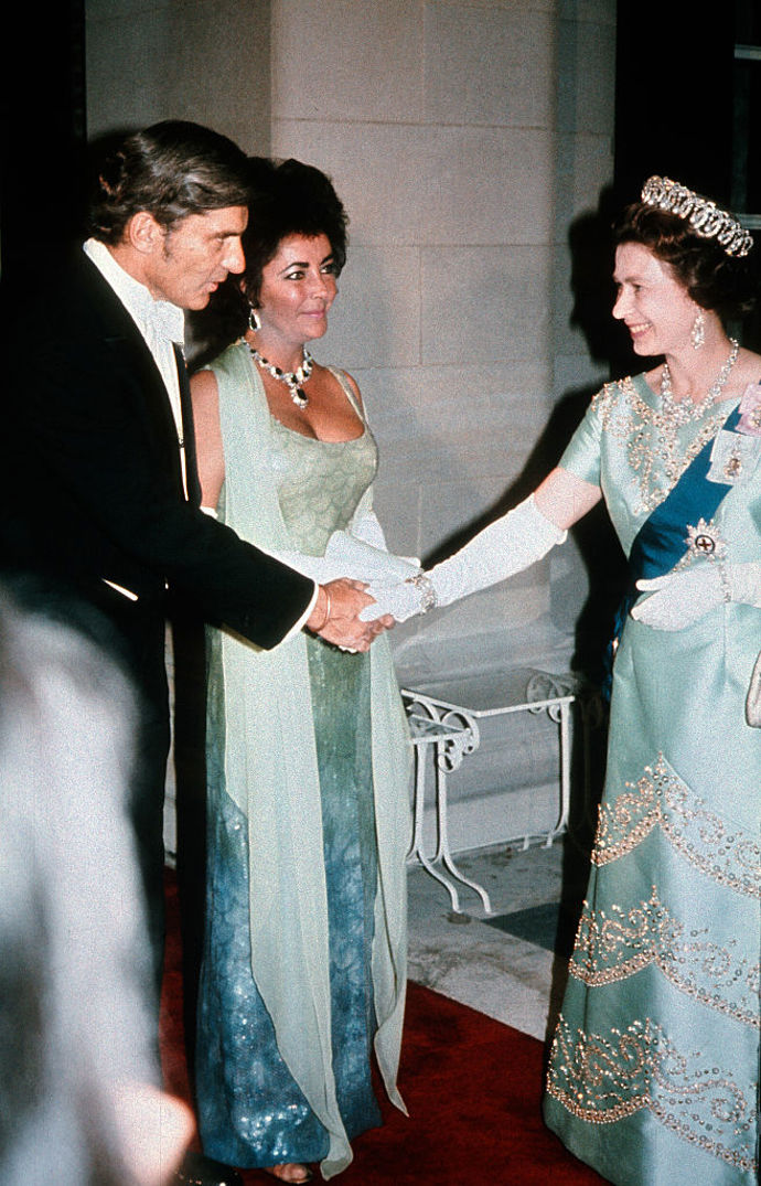 Herečka Elizabeth Taylor se s britskou královnou setkala v roce 1976 ve Washingtonu D.C. Na sobě měla modrozelenou róbu a výrazný náhrdelník.
