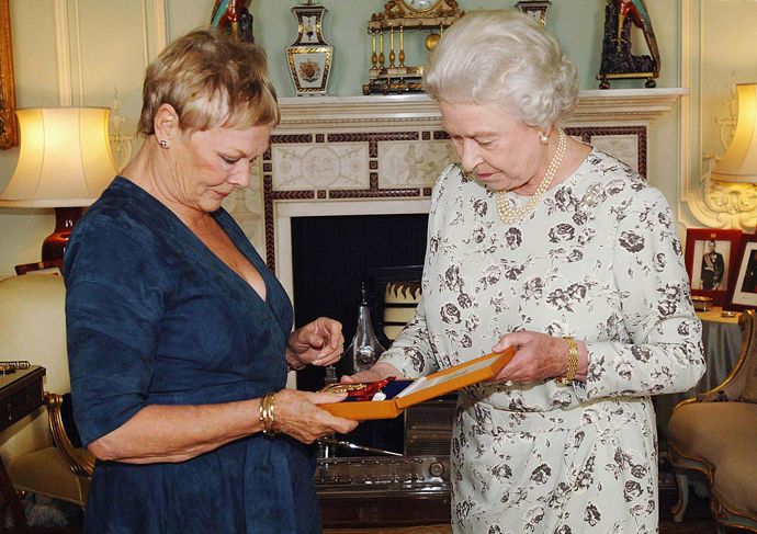 Herečka Judi Dench se s královnou Alžbětou II. setkala přímo v Buckhinghamském paláci v roce 2005. Na sobě měla jednoduché modré šaty.
