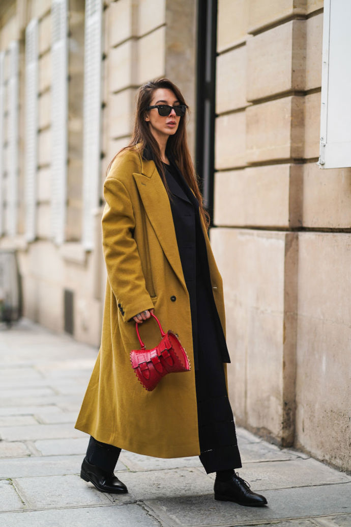 Estelle Chemouny zkombinovala černý outfit s kabátem v hrachové barvě a kontrastní červenou kabelkou značky Alaïa
