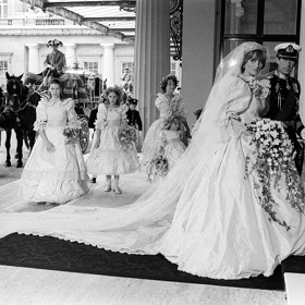 80. léta – Diana a Charles

Smutný příběh o nenaplněné lásce následníka britského trůnu a plaché dívky s laním pohledem netřeba znovu omílat.

Faktem však zůstává, že jejich svatební den vstoupil do dějin a nejedna holčička, přilepená u televizní obrazovky 29. července 1981, si v tu chvíli přála být princeznou.

Přispěly k tomu jistě i svatební šaty, které se stále pyšní několika nej. Tak za prvé, zdobila je úplně ta nejdelší vlečka – měřila úctyhodných 8 metrů a o tři metry dokonce předstihla i tu, kterou měla její budoucí tchýně Alžběta II. S róbou královny měla společné to, že ani jedny šaty nebyly čistě bílé, nýbrž se pyšnily odstínem slonové kosti a obě je měly pošité stejným počtem perliček – rovnými deseti tisíci.

A přestože boty nebyly pod dlouhou krinolínou (bylo na ni použito více jak 90 metrů látky) vidět, rozhodně stojí za zmínku. Každý střevíček byl pošitý 542 perlami a na podrážce byla ručně napsaná písmena D a C propletená srdcem.

Dianiny šaty navrhovali manželé Elizabeth a David Emanuelovi, kteří úzkostlivě dbali na to, aby nikdo jiný nespatřil tento skvost dříve než Diana slavnostně vstoupí do katedrály sv. Pavla.
