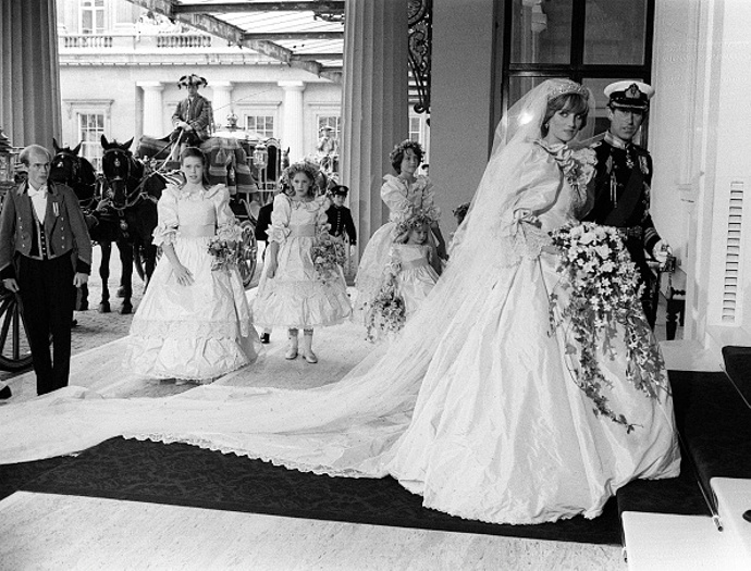 80. léta – Diana a Charles
Smutný příběh o nenaplněné lásce následníka britského trůnu a plaché dívky s laním pohledem netřeba znovu omílat.
Faktem však zůstává, že jejich svatební den vstoupil do dějin a nejedna holčička, přilepená u televizní obrazovky 29. července 1981, si v tu chvíli přála být princeznou.
Přispěly k tomu jistě i svatební šaty, které se stále pyšní několika nej. Tak za prvé, zdobila je úplně ta nejdelší vlečka – měřila úctyhodných 8 metrů a o tři metry dokonce předstihla i tu, kterou měla její budoucí tchýně Alžběta II. S róbou královny měla společné to, že ani jedny šaty nebyly čistě bílé, nýbrž se pyšnily odstínem slonové kosti a obě je měly pošité stejným počtem perliček – rovnými deseti tisíci.
A přestože boty nebyly pod dlouhou krinolínou (bylo na ni použito více jak 90 metrů látky) vidět, rozhodně stojí za zmínku. Každý střevíček byl pošitý 542 perlami a na podrážce byla ručně napsaná písmena D a C propletená srdcem.
Dianiny šaty navrhovali manželé Elizabeth a David Emanuelovi, kteří úzkostlivě dbali na to, aby nikdo jiný nespatřil tento skvost dříve než Diana slavnostně vstoupí do katedrály sv. Pavla.
80. léta – Diana a Charles
Smutný příběh o nenaplněné lásce následníka britského trůnu a plaché dívky s laním pohledem netřeba znovu omílat.
Faktem však zůstává, že jejich svatební den vstoupil do dějin a nejedna holčička, přilepená u televizní obrazovky 29. července 1981, si v tu chvíli přála být princeznou.
Přispěly k tomu jistě i svatební šaty, které se stále pyšní několika nej. Tak za prvé, zdobila je úplně ta nejdelší vlečka – měřila úctyhodných 8 metrů a o tři metry dokonce předstihla i tu, kterou měla její budoucí tchýně Alžběta II. S róbou královny měla společné to, že ani jedny šaty nebyly čistě bílé, nýbrž se pyšnily odstínem slonové kosti a obě je měly pošité stejným počtem perliček – rovnými deseti tisíci.
A přestože boty nebyly pod dlouhou krinolínou (bylo na ni použito více jak 90 metrů látky) vidět, rozhodně stojí za zmínku. Každý střevíček byl pošitý 542 perlami a na podrážce byla ručně napsaná písmena D a C propletená srdcem.
Dianiny šaty navrhovali manželé Elizabeth a David Emanuelovi, kteří úzkostlivě dbali na to, aby nikdo jiný nespatřil tento skvost dříve než Diana slavnostně vstoupí do katedrály sv. Pavla.