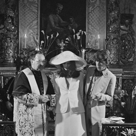 70. léta – Mick Jagger a Bianca Jagger

Svatba zbavená všech tradic a zvyků, tak by se dal nazvat sňatek Micka Jaggera a jeho extravagantní ženy Biancy.

Modelka a právnička nikaragujského původu Bianca des Macias ráda vybočovala z davu, ostatně to byl prý jeden z důvodů, proč tak zaujala rozjíveného frontmana skupiny Rolling Stones. Je tedy nad míru jasné, že zde bychom klasické svatební šaty se spořádanou hostinou jen těžko pohledali.

Bianca ve svůj velký den 12. května 1971 oslnila přítomné hosty v Saint Tropez bílým kostýmkem z dílny návrhářského mistra Yvese Saint Laurenta. A to by nebyla ona, aby ani ve svatební den trochu nešokovala. Pod bílým sakem totiž už nic jiného neměla. Šušká se, že tento módní výstřelek musela nevěsta zvolit kvůli tomu, že vzhledem ke svému těhotenství se do připravené košile již nevešla.

A přestože bychom tomu páru jistě přáli, aby pro ně platilo, ono pohádkové „žili šťastně až do smrti“, v tomto případě se zázrak nekonal a rockový bouřlivák nebyl zkrocen. Jako důvod rozvodu, sedm let od svatby uvedla Bianca Jagger cizoložství.
