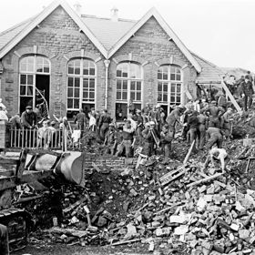 Hornická katastrofa ve Walesu – 1966

Černým písmem se do paměti královny Alžběty II. zapsal 21. říjen 1966. Ve vesnici Aberfan v jižním Walesu totiž došlo k hornické katastrofě, při které zemřelo 116 dětí a 28 dospělých. Zatímco princ Filip přijel do Aberfanu den po neštěstí, královna s návštěvou otálela a údajně ji odložila kvůli tomu, aby její přítomnost neodvrátila pozornost od záchranných a zotavovacích snah. Blízcí lidé, včetně jejího bývalého komorníka lorda Charterise, následně řekli, že královna Alžběta II. litovala, že do Aberfanu nepřijela dříve.
