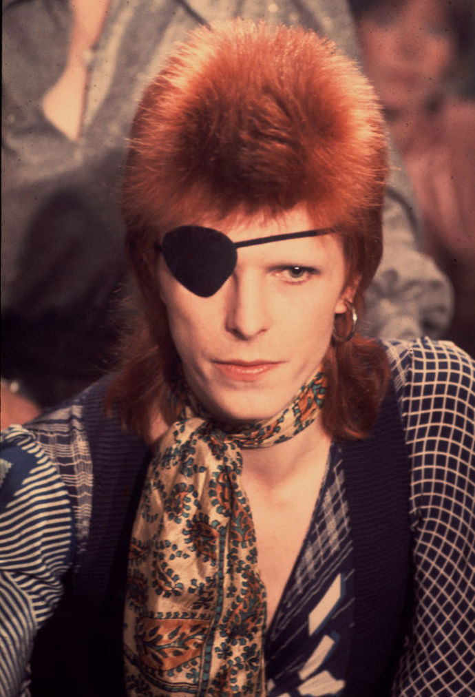 V období Ziggy Stardust nosil David Bowie kromě zrzavých vlasů a tyrkysových stínů také pásku přes oko. Nejprve mu sloužila jako ochrana citlivého oka, look s ní si ale natolik oblíbil, že ji pak nosil i jako součást kostýmu na pódium.
V období Ziggy Stardust nosil David Bowie kromě zrzavých vlasů a tyrkysových stínů také pásku přes oko. Nejprve mu sloužila jako ochrana citlivého oka, look s ní si ale natolik oblíbil, že ji pak nosil i jako součást kostýmu na pódium.