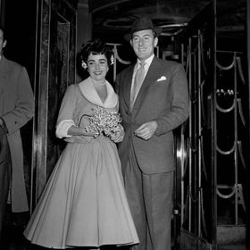 Michael Wilding, 21. února 1952

Po krátkém manželství s Conradem Hiltonem se Elizabeth provdala za Michaela Wildinga. Nutno dodat, že Wilding byl o 20 let starší než Elizabeth, a tak nevěsta přirozeně zvolila zdrženlivější svatební look s výrazným bílým límečkem. Také v tomto případě se o svatební šaty postarala Helen Rose. 

Sňatek vydržel až do roku 1957, kdy se provalilo Lizino randění s filmovým producentem Michaelem Toddem.
