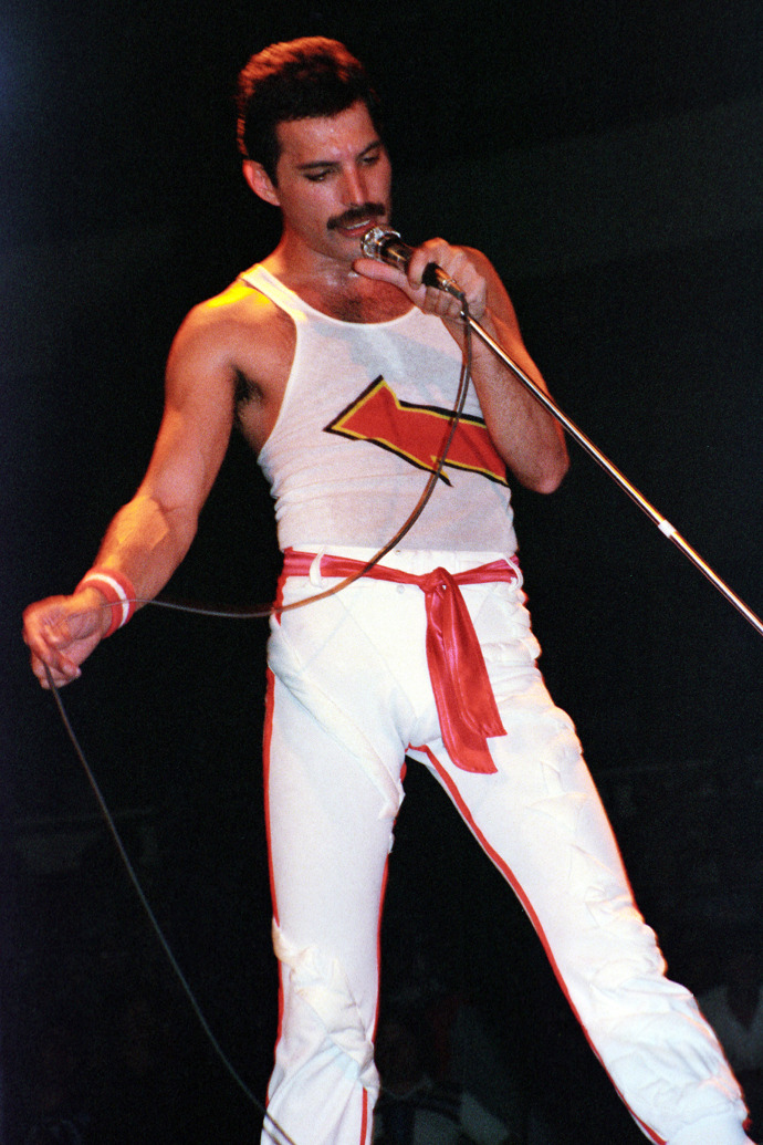 Na začátku 80. let si Freddie Mercury oblíbil světlé kalhoty s tílka. 
