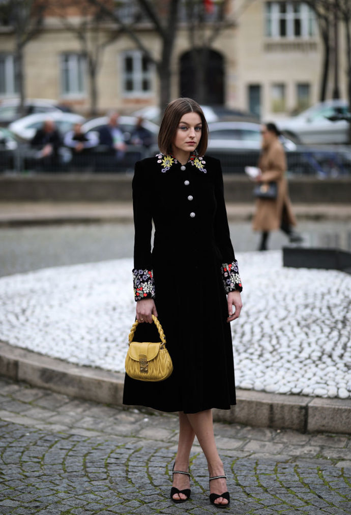 Černý elegantní kabát rozzáří barevné výšivky na rukávech i kolem krku.
