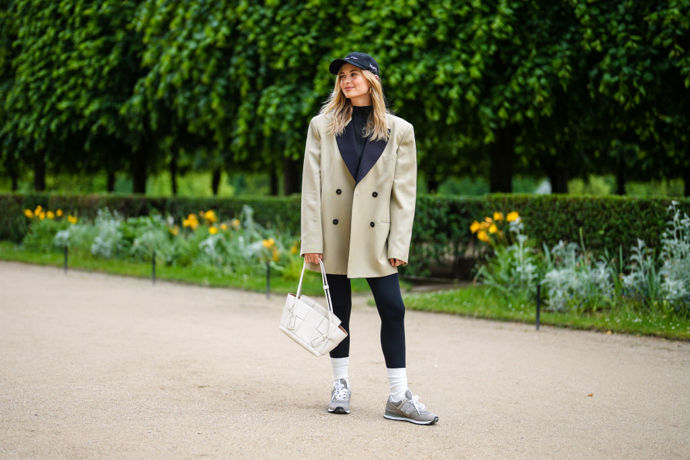 Xenia Adonts v oversized saku v kombinaci s legínami, New Balance teniskami a kšiltovkou.
