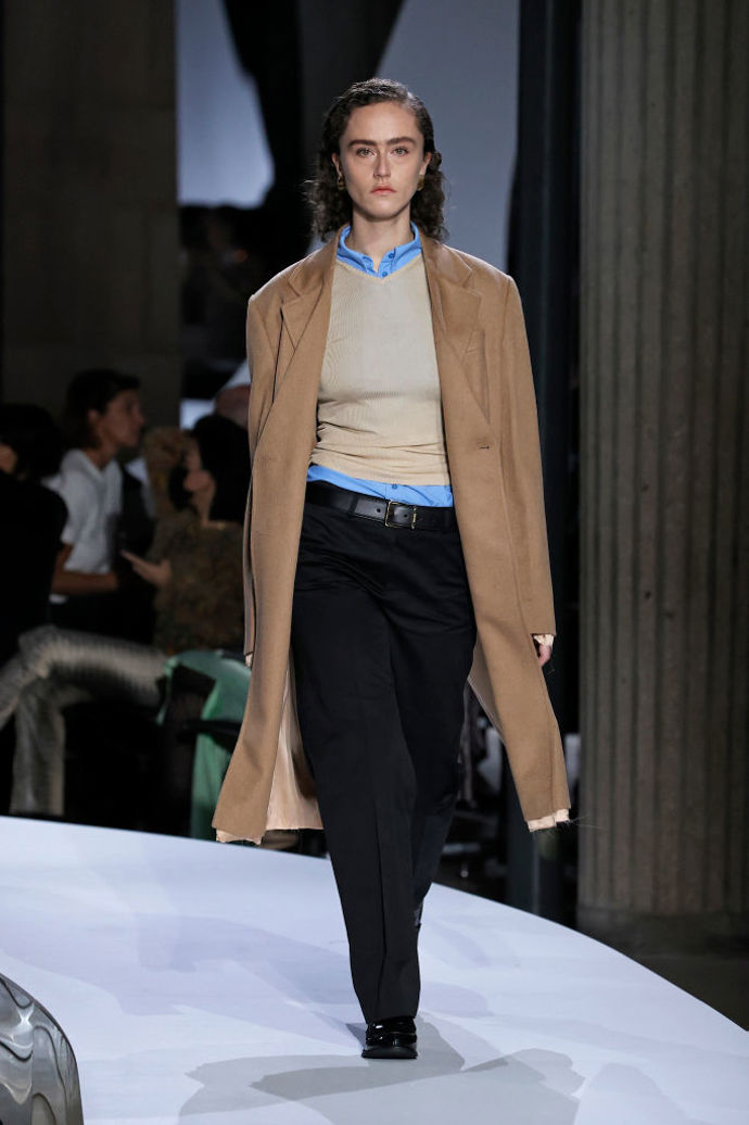 Na přehlídce Miu Miu pro aktuální sezónu se objevil i klasický look v podobě modré košile, světlého svetříku, béžového kabátu a černých formálnějších kalhot s nízkým pasem a páskem.
