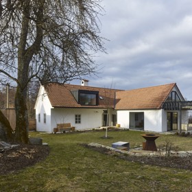 Architekt přirozeně začlenil sklo a přírodní ocel do venkovské stavby. Díky tomu světlo a prostor dominují a vytváří DNA domu s atmosférou podpořenou mladým uměním. Pomyslným srdcem objektu se stala jídelna s kuchyní, otevřená do krovu, v němž dominuje kovová lávka propojující galerii se skleněnou terasou.
