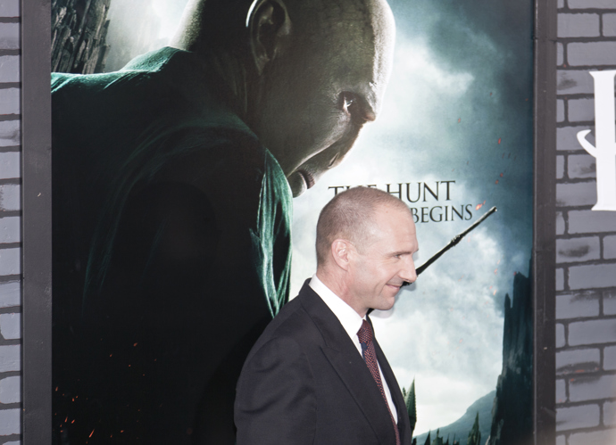Ralph Fiennes u plakátu, na kterém je vyobrazen Lord Voldemort. 
