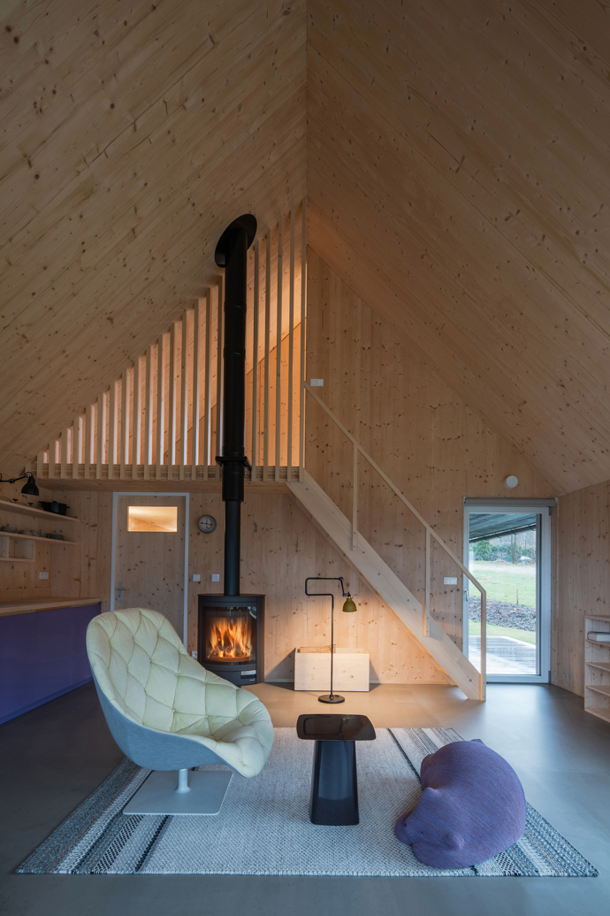 Modrý šindelový obklad a elegantní bílé rámy oken vytvářejí kontrast, který nemůžete přehlédnout. Architektka Markéta Cajthamlová a její tým se postarali o každý detail, ať už jde o interiér plný dřeva nebo promyšlenou dispozici, která nabídne vše, co potřebujete.
