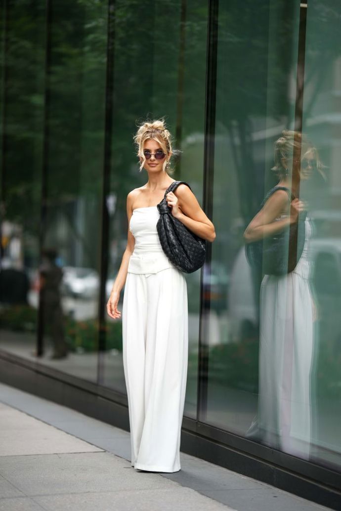 Xenia Adonts v celobílém outfitu doplněném oversize černou proplétanou kabelkou
