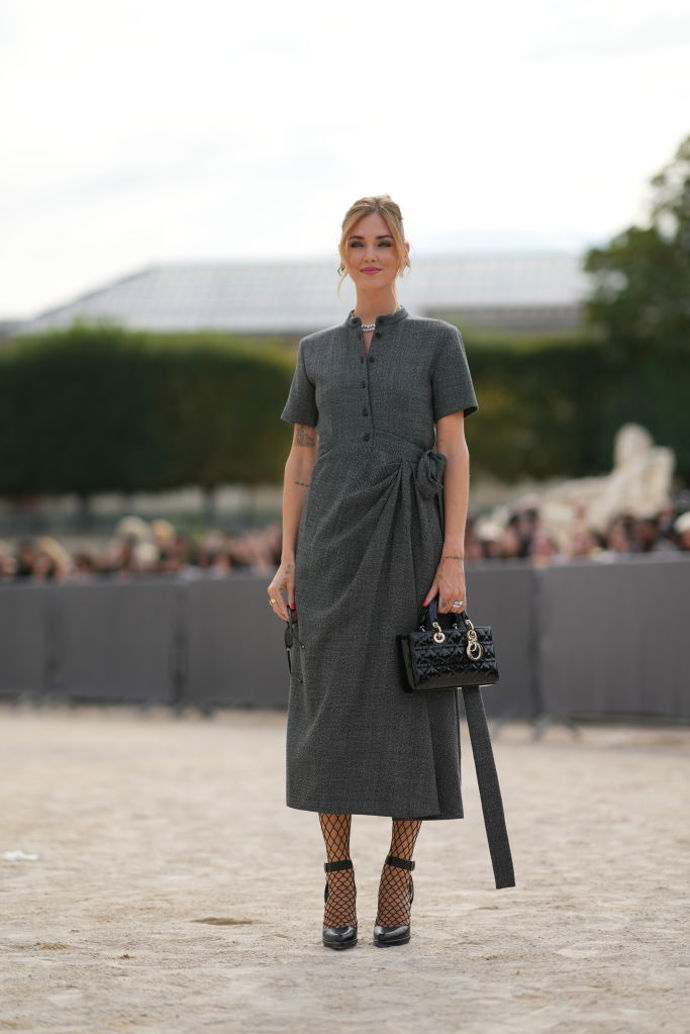 Chiara Ferragni na přehlídku Dior oblékla střídmé šedé elegantní šaty, síťované punčochy a look doplnila kabelkou Lady Dior.
