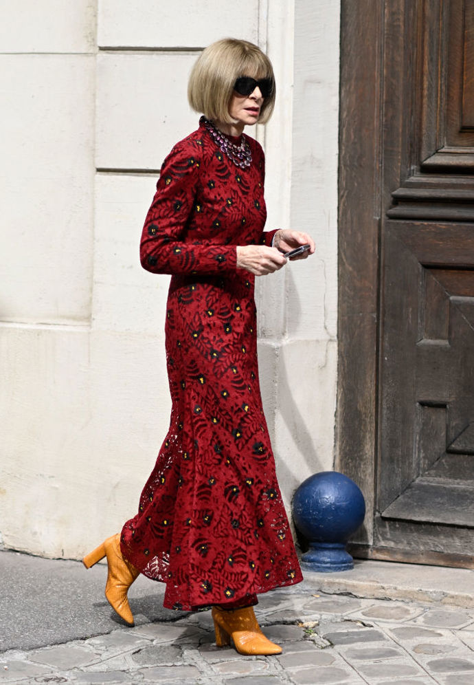 Anna Wintour vyrazila na pařížský fashion week v červených vzorovaných šatech, které doplnila oranžovými kozačkami.
