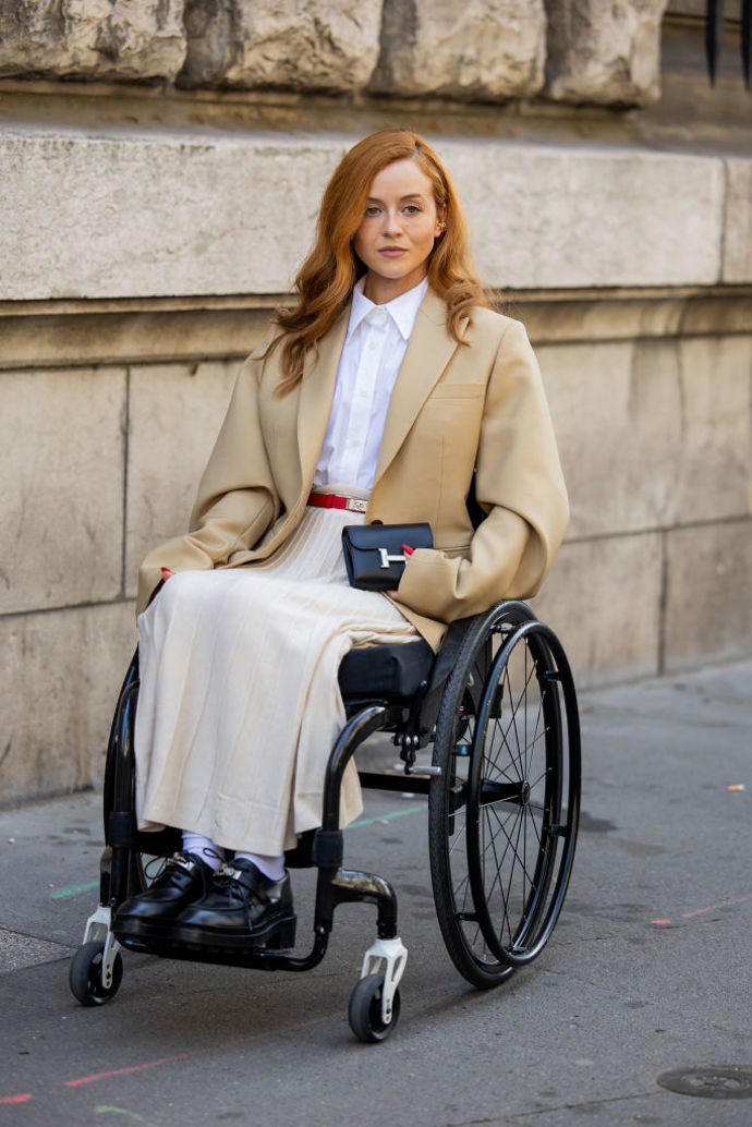 Ani ženám na invalidním vozíku nemusí chybět styl! Kombinace bílé košile, béžového saka a krémové plisované sukně v kombinaci s černými masivnějšími polobotkami je naprosto nadčasová.
