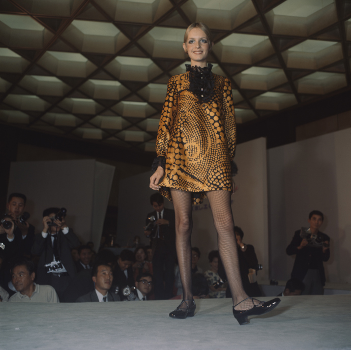 Twiggy v oranžovo-černých mini šatech na módní přehlídce v japonské Osace v říjnu 1967. 
