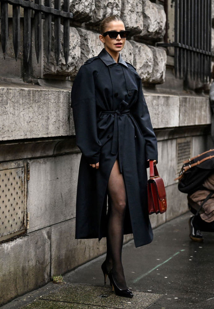 Caro Daur oblékla oversized trenčkot, burgundy kabelku Hermès a černé lakované lodičky.
