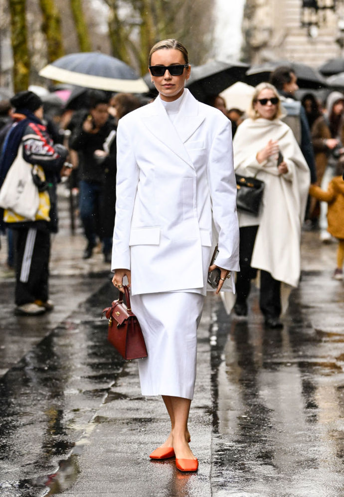 Jak oživit celobílý outfit? Efektním detailem v podobě oranžových pantoflíčků.

