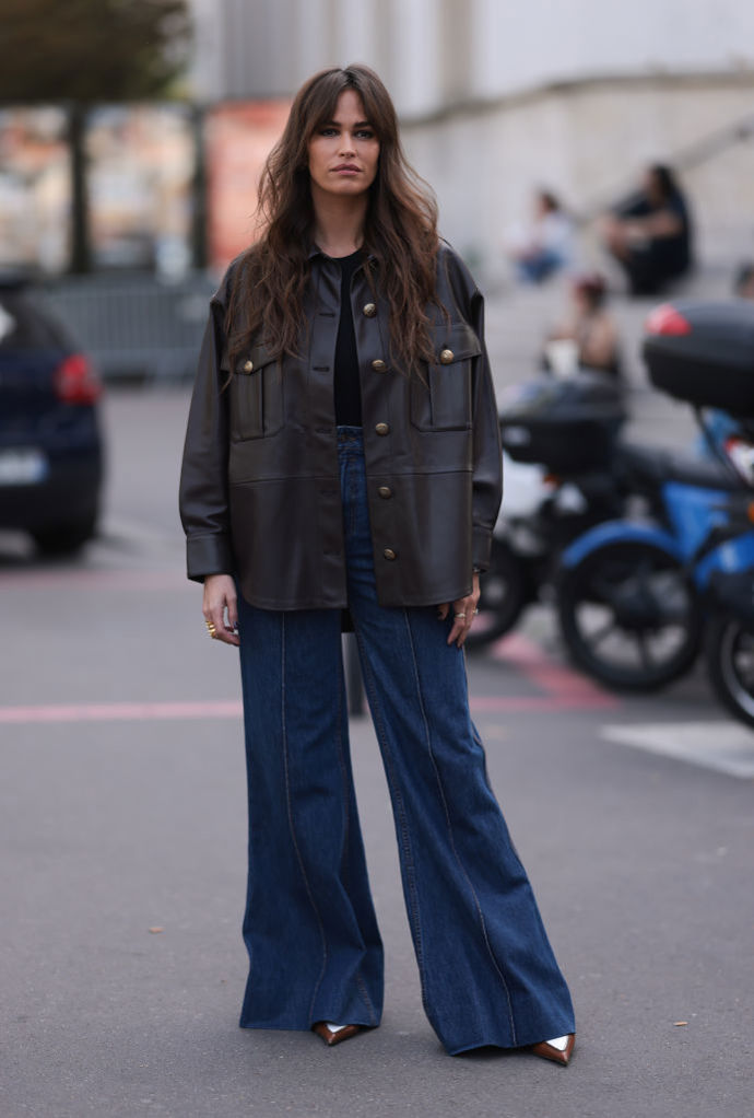 Tmavě modré širší džíny, boty se špičatou špičkou a tmavě hnědá kožená bunda vytvoří stylový look inspirovaný začátkem milénia.
