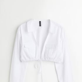 Zkrácená bílá košile z tkané látky. Má límec a hluboký průstřih do véčka se stahovací šňůrkou v dolním lemu. Značka H&M,, přibližná cena 599 Kč. Během Dnů Marianne platí sleva 20 % při nákupu nad 800 Kč. 
