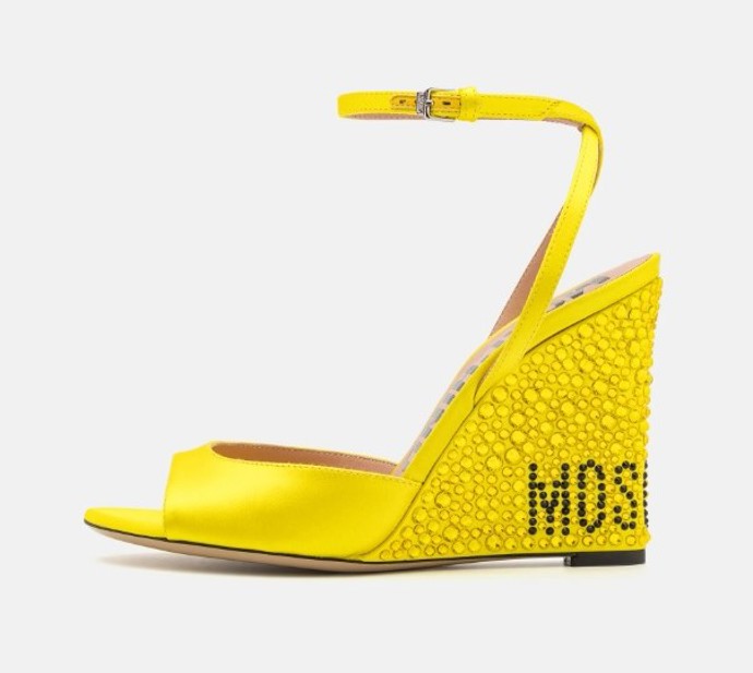 Výrazné žluté sandálky na vysokém klínu zdobeném transparentními pecičkami a logem působí zároveň elegantně i extravagantně, Moschino, cena přibližně 20 400 Kč. Během Dnů Marianne pořídíte například na Zelando.cz se slevou až 25 %.

