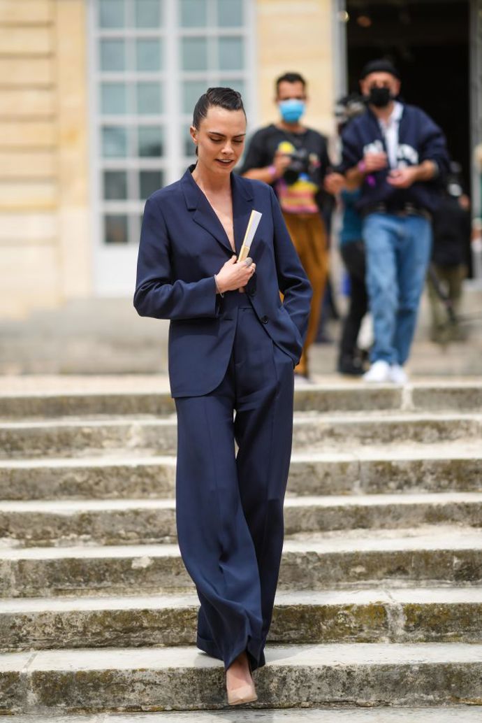 Námořnicky modrý kalhotový kostým oblékla na pařížském fashion weeku Cara Delevingne.
