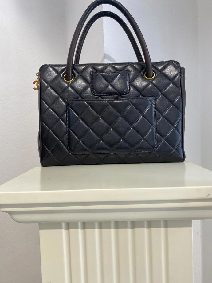 Chanel Black Quilted Leather Bag z roku 1996/1997. Má překrásné lemované horní rukojeti, vnější kapsy (2 otevřené kapsy a 1 mini kapsa). Horní zapínání na zip. CC - přívěsek s logem CHANEL jako tah na zip. Vínová kožená podšívka dělá tuto kabelku vysoce elegantní.
