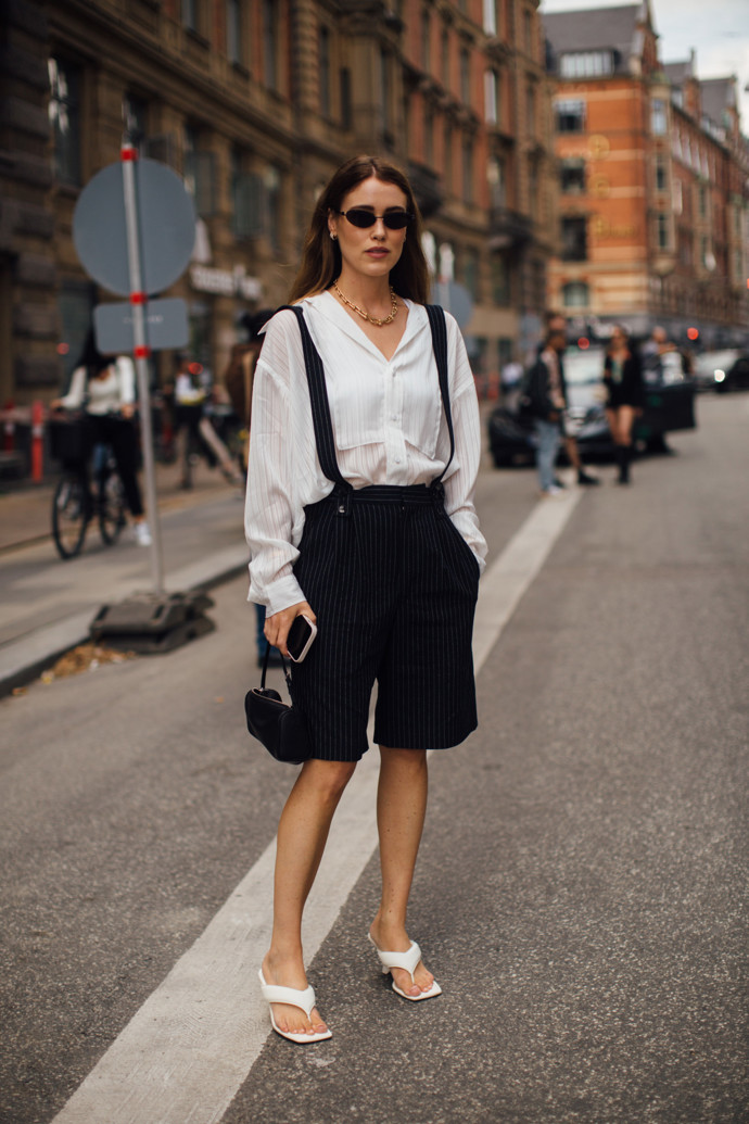 Outfit v tak trochu pánském stylu vytvoříte kombinací černých bermud s kšandami a bílé košile. Ženskost outfitu dodáte pantoflíčky na mírném podpatku.
