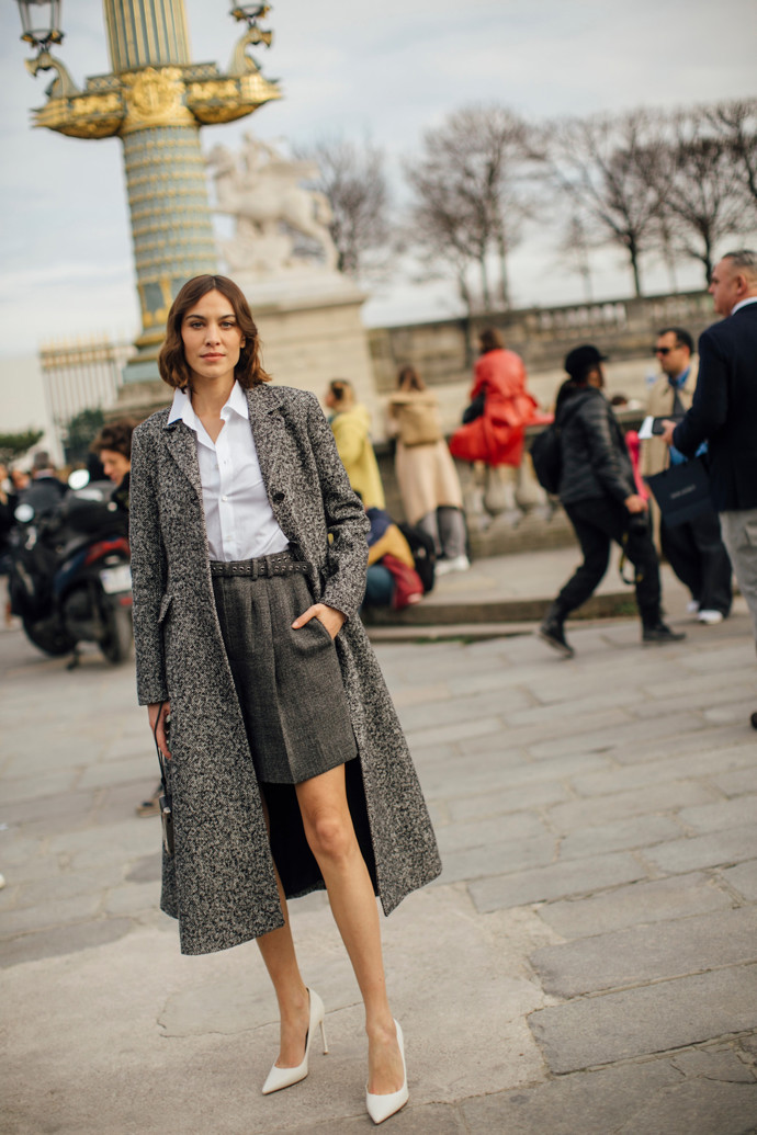Alexa Chung oblékla na pařížský fashion week komplet vlněných bermud a kabátu a přidala bílou košili a bílé lodičky.
