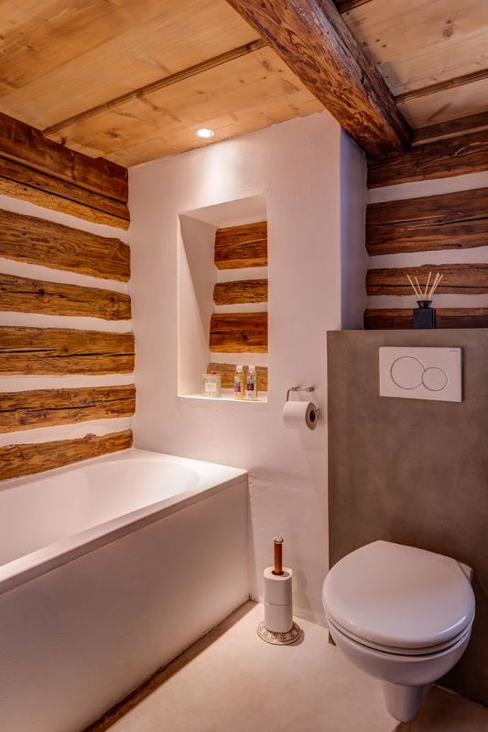 Moderní koupelna v roubence kombinuje minimalistický design s přírodními prvky, kde čisté linie a luxusní materiály vytvářejí harmonický kontrast.
