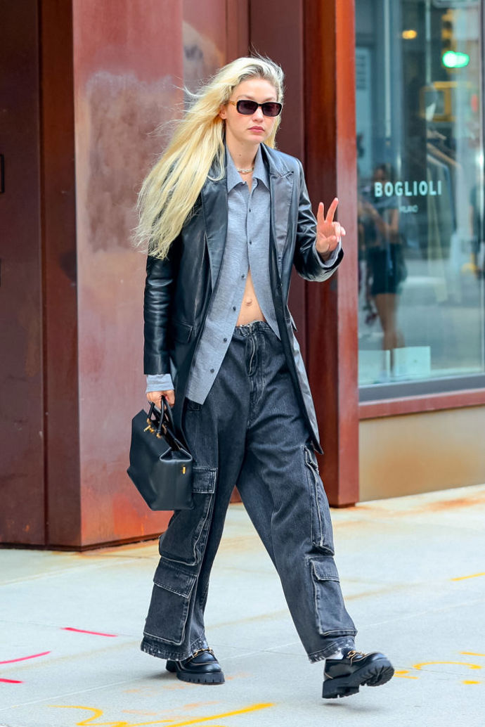 Modelka Gigi Hadid oblékla kožené sako k šedé košili a širokým džínovým kapsáčům.
