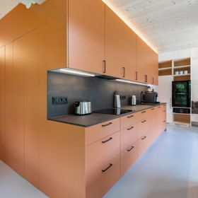 Dřevem obložená zabudovaná kuchyňská linka s moderními spotřebiči dodává interiéru příjemný a stylový kontrast mezi tradičním materiálem a současnou funkčností.
