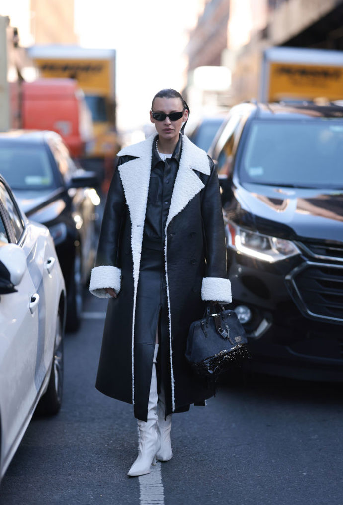 Černý shearling kabát se hodí například ke koženým košilovým šatům a světlým kozačkám.

