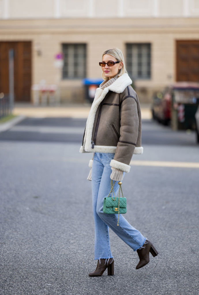 Světle modré džíny se k shearling bundě v hnědé barvě skvěle hodí, outfit můžete barevně rozbít zelenou kabelkou.
