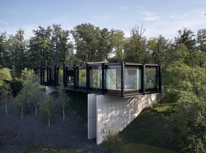 V malebné vilové čtvrti nad Berounkou vyrostla moderní vila Sidonius, která redefinuje pojetí luxusního bydlení. Postavená na prudkém svahu pomocí ocelové mostní konstrukce, nabízí obyvatelům nejen výhledy na krásy Českého krasu a Prahu, ale také originální architektonické a technologické řešení.
