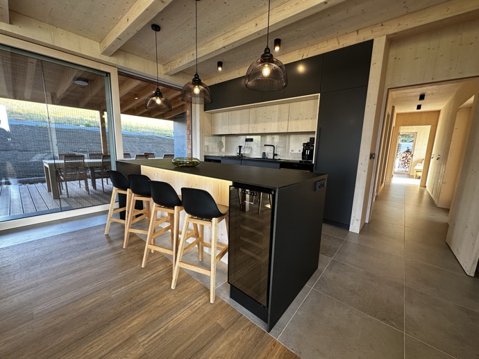 Přírodní minimalistický design a decentní barevná paleta zajišťuje dokonalou eleganci. Velkými okny proudí dovnitř mnoho světla, přes které je možné pozorovat malebnou krajinu, která celou chatu obklopuje. Fasádu domu tvoří ručně štípané modřínový šindel, zatímco uvnitř je obloženo smrkovými biodeskami.

