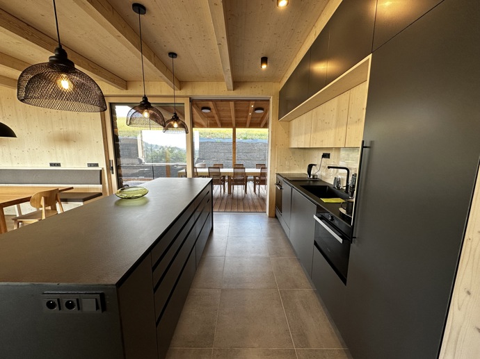 Přírodní minimalistický design a decentní barevná paleta zajišťuje dokonalou eleganci. Velkými okny proudí dovnitř mnoho světla, přes které je možné pozorovat malebnou krajinu, která celou chatu obklopuje. Fasádu domu tvoří ručně štípané modřínový šindel, zatímco uvnitř je obloženo smrkovými biodeskami.
