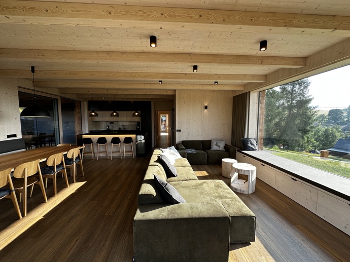 Přírodní minimalistický design a decentní barevná paleta zajišťuje dokonalou eleganci. Velkými okny proudí dovnitř mnoho světla, přes které je možné pozorovat malebnou krajinu, která celou chatu obklopuje. Fasádu domu tvoří ručně štípané modřínový šindel, zatímco uvnitř je obloženo smrkovými biodeskami.
