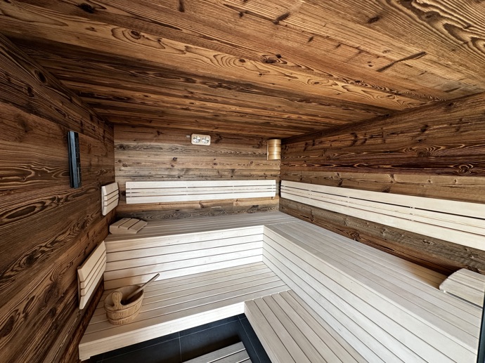 Přírodní minimalistický design a decentní barevná paleta zajišťuje dokonalou eleganci. Velkými okny proudí dovnitř mnoho světla, přes které je možné pozorovat malebnou krajinu, která celou chatu obklopuje. Fasádu domu tvoří ručně štípané modřínový šindel, zatímco uvnitř je obloženo smrkovými biodeskami.
