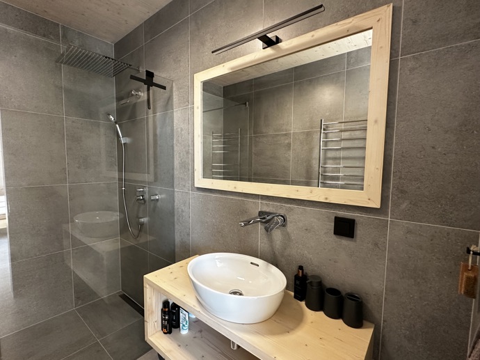 Přírodní minimalistický design a decentní barevná paleta zajišťuje dokonalou eleganci. Velkými okny proudí dovnitř mnoho světla, přes které je možné pozorovat malebnou krajinu, která celou chatu obklopuje. Fasádu domu tvoří ručně štípané modřínový šindel, zatímco uvnitř je obloženo smrkovými biodeskami.
