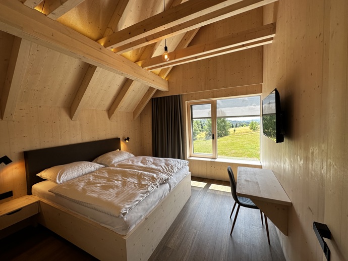 Přírodní minimalistický design a decentní barevná paleta zajišťuje dokonalou eleganci. Velkými okny proudí dovnitř mnoho světla, přes které je možné pozorovat malebnou krajinu, která celou chatu obklopuje. Fasádu domu tvoří ručně štípané modřínový šindel, zatímco uvnitř je obloženo smrkovými biodeskami.
