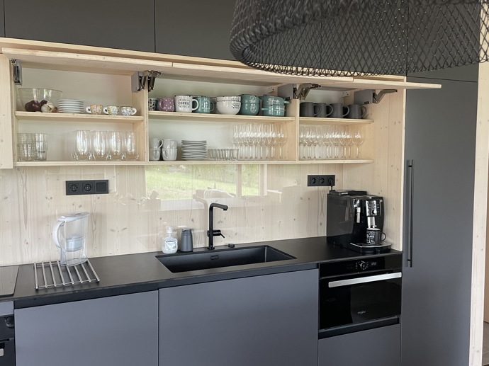 Přírodní minimalistický design a decentní barevná paleta zajišťuje dokonalou eleganci. Velkými okny proudí dovnitř mnoho světla, přes které je možné pozorovat malebnou krajinu, která celou chatu obklopuje. Fasádu domu tvoří ručně štípané modřínový šindel, zatímco uvnitř je obloženo smrkovými biodeskami.
