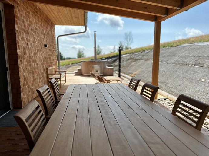 Přírodní minimalistický design a decentní barevná paleta zajišťuje dokonalou eleganci. Velkými okny proudí dovnitř mnoho světla, přes které je možné pozorovat malebnou krajinu, která celou chatu obklopuje. Fasádu domu tvoří ručně štípané modřínový šindel, zatímco uvnitř je obloženo smrkovými biodeskami.
