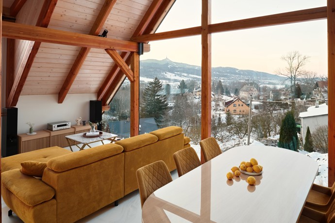 Majestátní Ještěd se nestal jen výhledem z okna, ale inspirací pro celý interiér. Architektka Taťána Kandratovičová vytvořila prostor, kde se moderní design prolíná s přírodními materiály a tradicí roubených staveb.
